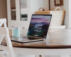 Imagen de un portátil encima de una mesa en un salon con interior de color blanco