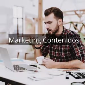 Imagen de hombre con camisa a cuadros de color rojo y negro sentado en un escritorio con un portátil y un café en BarmetMedia.