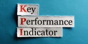 Recorte de palabras en un papel de Key, Performance e Indicator sobre una superficie celeste indicando los PKIs esenciales de Google Ads por BarmetMedia.