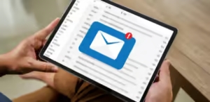 Manos sosteniendo una tablet con un logotipo virtual de una carta con un simbolo de exclamación.